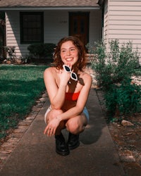 a woman in a bikini crouching in front of a house