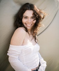 a young woman smiling while leaning against a tent